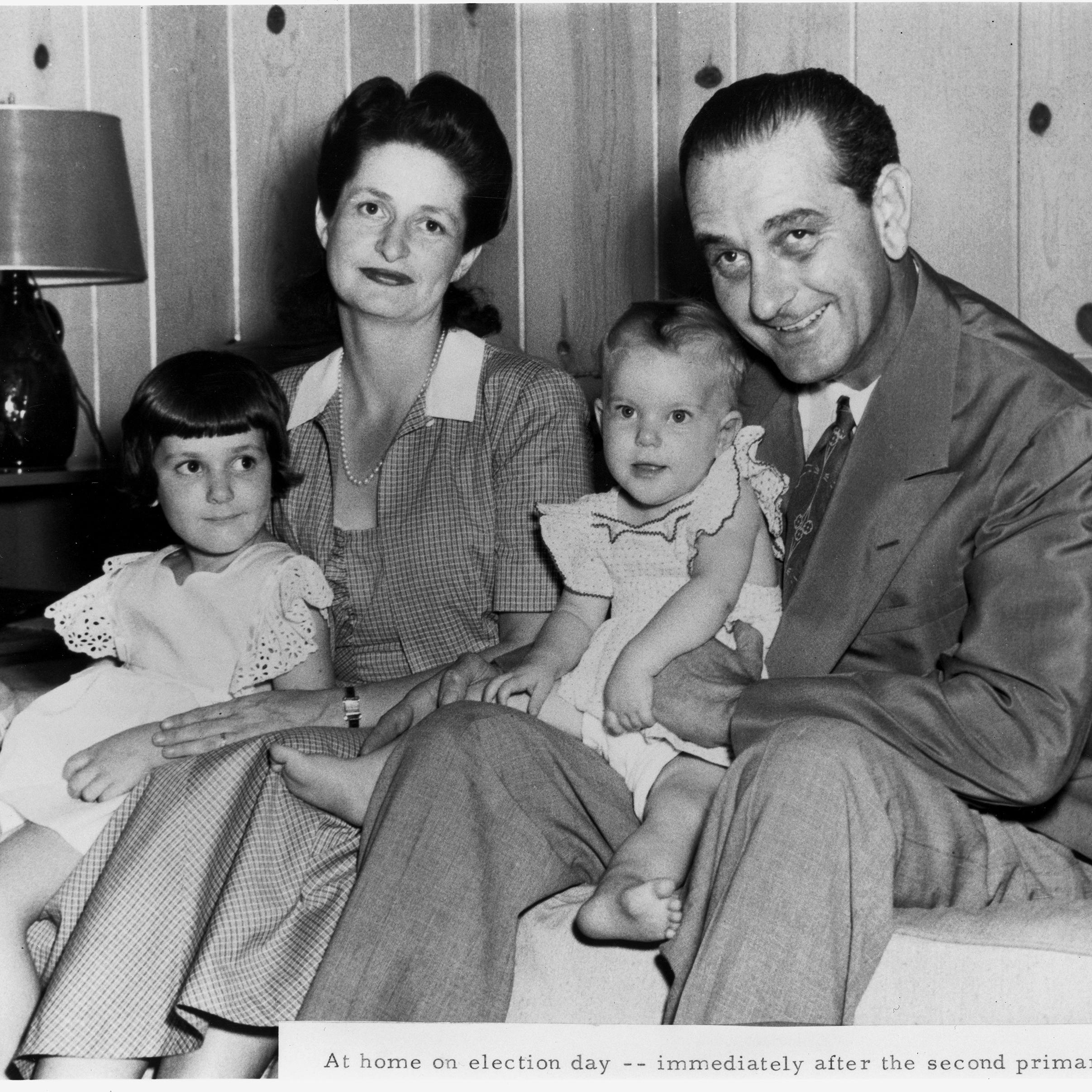 Lady Bird and Lyndon Johnson sit on a sofa with their two small girls, Lynda and Luci.